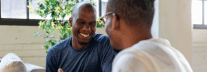 Two men smiling and laughing together, symbolising positive social interactions and the importance of mental health support in the workplace.