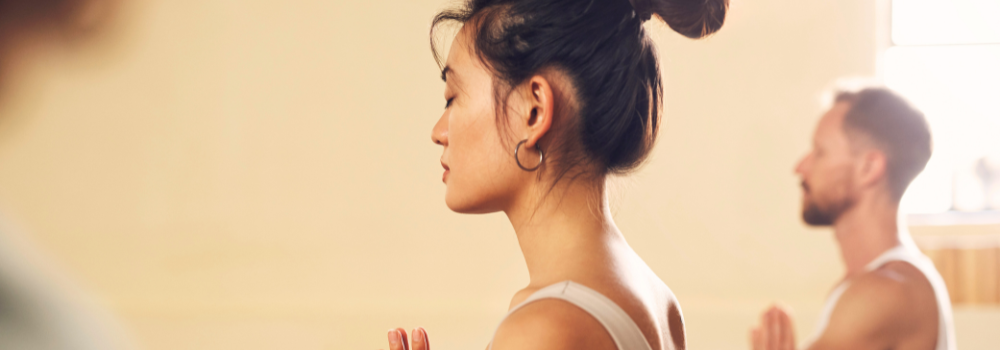 People practising mindfulness and meditation in a calm, indoor setting.