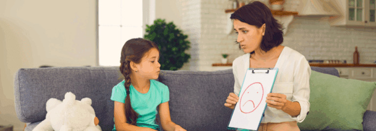 Child and CAMHS clinician sitting on a sofa during a therapy session, using visual tools to support emotional expression.