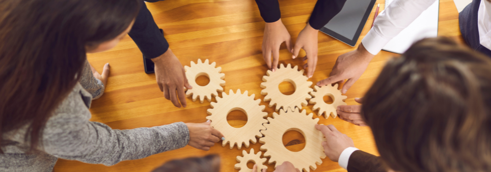 Colleagues working together with interlocking gears, symbolising peer support and teamwork in mental health services.