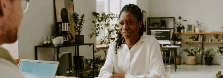A professional woman smiling during a conversation in an office setting, representing recruitment and workplace opportunities in mental health.