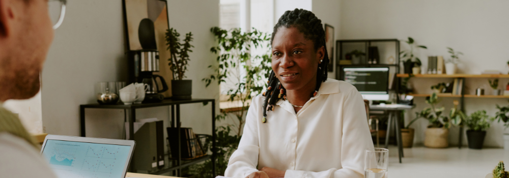 A professional woman smiling during a conversation in an office setting, representing recruitment and workplace opportunities in mental health.