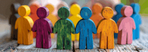 Colourful wooden human figures standing together in a group, symbolising inclusion, diversity and unity in mental health services.