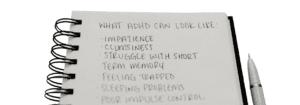 Handwritten notebook listing common ADHD symptoms including impatience, memory difficulties, sleep problems and impulse control challenges.